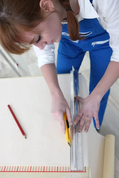 Woman cutting length of wallpaper — Zdjęcie stockowe