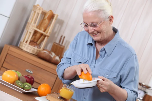 Starší paní mačkání pomerančová šťáva — Stock fotografie