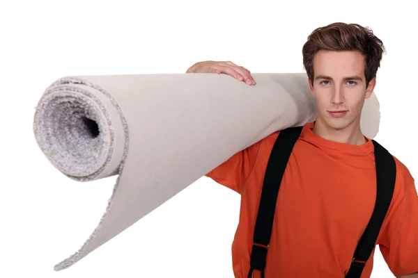Hombre llevando un rollo de alfombra — Foto de Stock