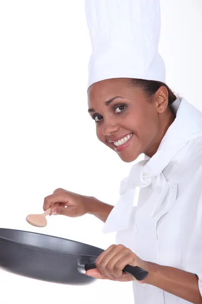 Vrouwelijke chef-kok in uniform met een diepe koekenpan en houten lepel — Stockfoto