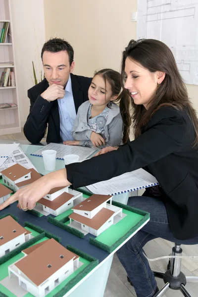 Família jovem olhando para habitação modelo — Fotografia de Stock