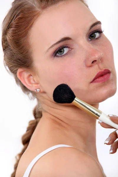 Jovem mulher colocando maquiagem em seu rosto — Fotografia de Stock