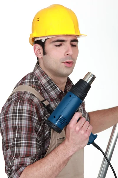 Tradesman blowing on his screw gun — Stock Photo, Image