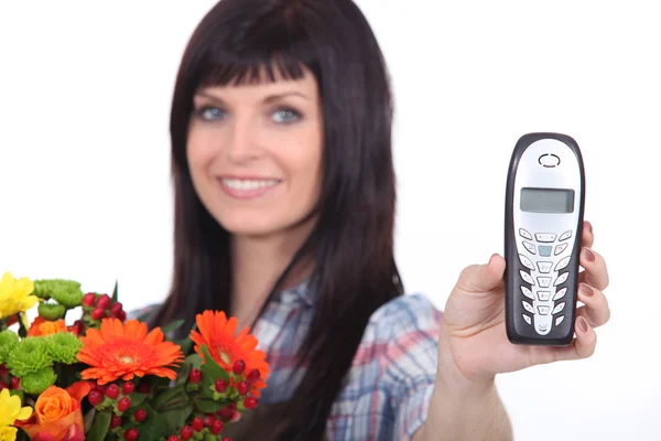 Девушка-флористка держит мобильный телефон — стоковое фото