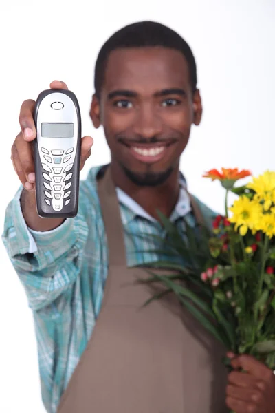 Florista sorrindo e segurando um telefone — Fotografia de Stock