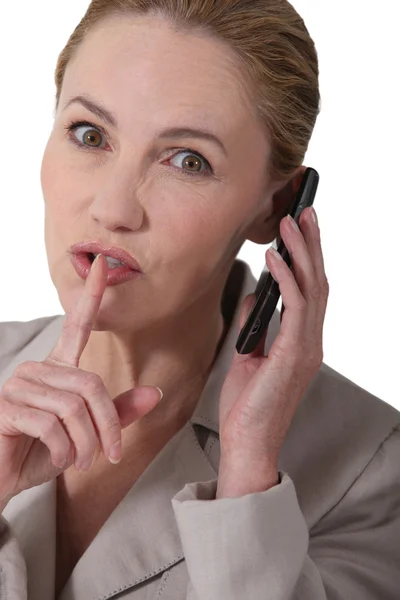 Γυναίκας, υποδηλώνοντας την ησυχία ενώ εκμετάλλευση ένα τηλέφωνο — Φωτογραφία Αρχείου