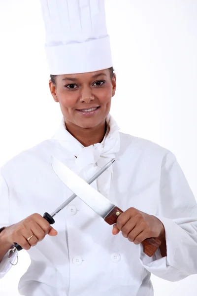 Кухар заточує кухонний ніж зі сталі — стокове фото
