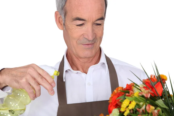 Uomo anziano spruzzando acqua sui fiori — Foto Stock