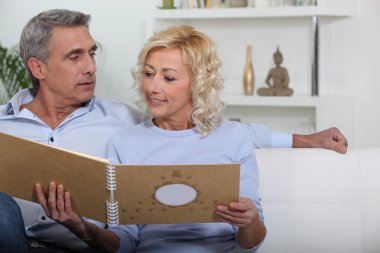 Mature couple looking at photo album clipart