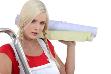 Very pretty young woman preparing to wallpaper a room clipart