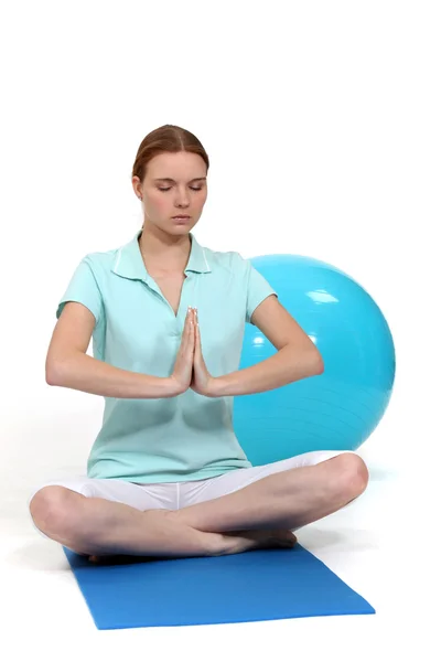Mujer sentada en posición de yoga por bola de ejercicio — Foto de Stock