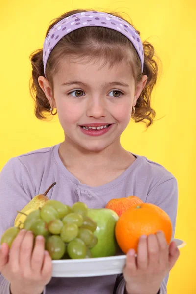 Little girl with an armful of fruit — Stock Photo, Image