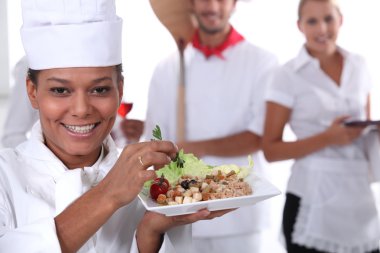 A cook holding a dish, a pizza cook and a waitress dressed in uniform clipart