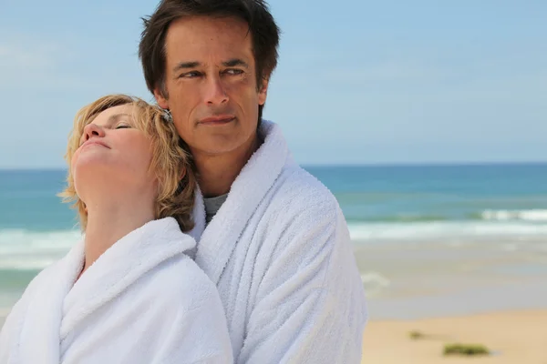 Couple in bathrobes on the beach — Stock Photo, Image