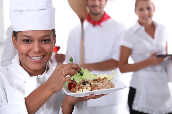 Un cuisinier tenant un plat, un cuisinier de pizza et une serveuse vêtue d'uniforme — Photo