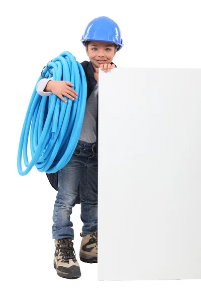 Ung pojke som låtsas vara en rörmokare med en styrelse tomt för ditt meddelande — Stockfoto