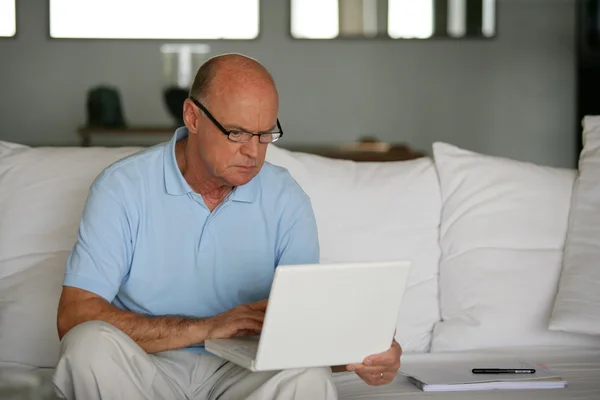 대머리 남자 노트북으로 소파에 앉아 — 스톡 사진