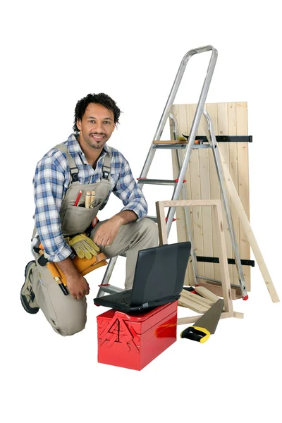 Торговец позирует со своими строительными материалами, инструментами и ноутбуком — стоковое фото
