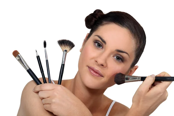 Brunette holding a selection of make-up brushes — Stock Photo, Image