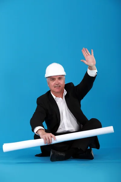 Architect sat cross-legged waving hand — Stock Photo, Image
