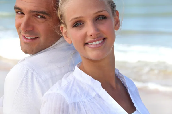 Couple back to back on the beach — Stock Photo, Image
