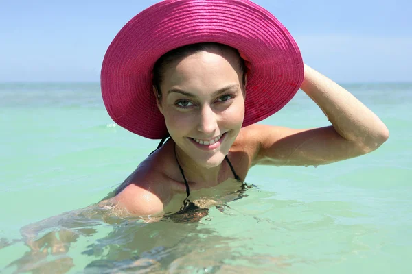 Женщина, купающаяся в море в розовой шляпе — стоковое фото