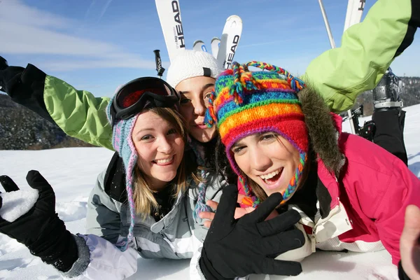 Três amigos deitados na neve com equipamento de esqui — Fotografia de Stock
