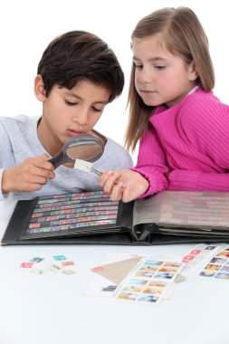 Two kids collecting stamps. clipart