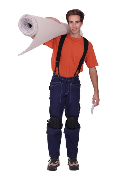 Homem carregando rolo de tapete sobre ombro — Fotografia de Stock