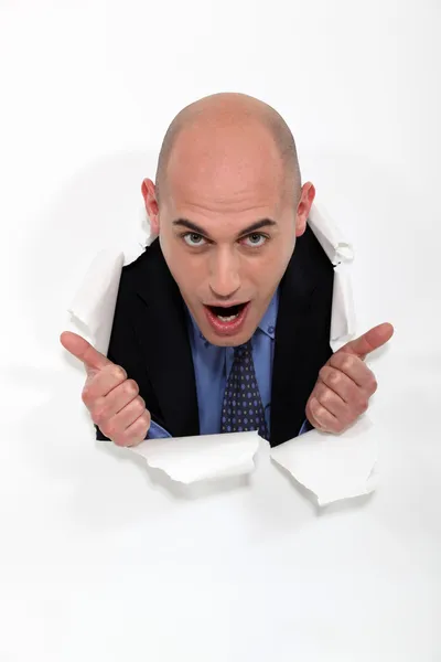Homem espreitando através do furo de papel rasgado — Fotografia de Stock