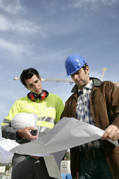Werknemers in de bouw te kijken naar een blauwdruk — Stockfoto