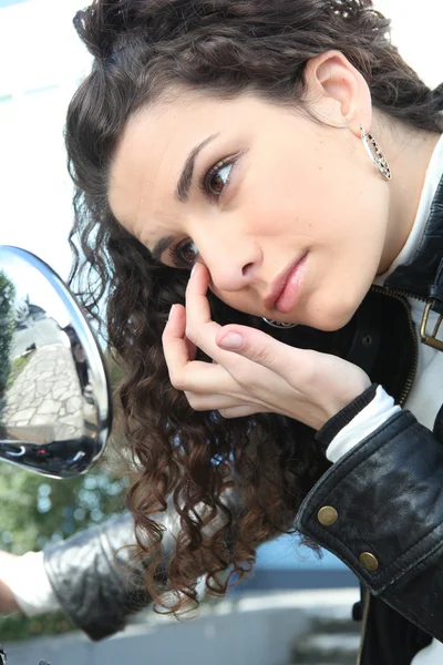 Mulher olhando seu olho no espelho retrovisor — Fotografia de Stock