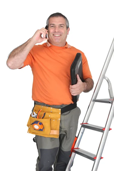 Man on cellphone with ladder and plumbing tools — Stock Photo, Image
