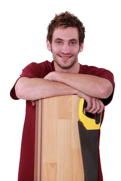 Όμορφος νεαρός άνδρας με ένα floorboard και το πριόνι — Φωτογραφία Αρχείου
