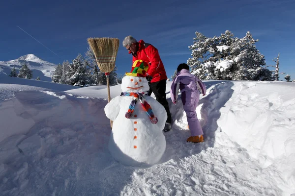 Father and daughter playing with snowman — Stock Photo, Image