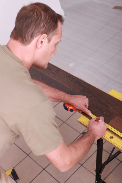 男子用铅笔划出强化木地板 — 图库照片