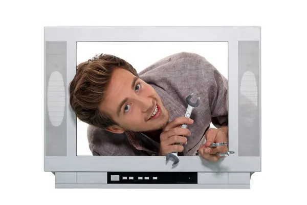 Man with a spanner inside a television — Stock Photo, Image