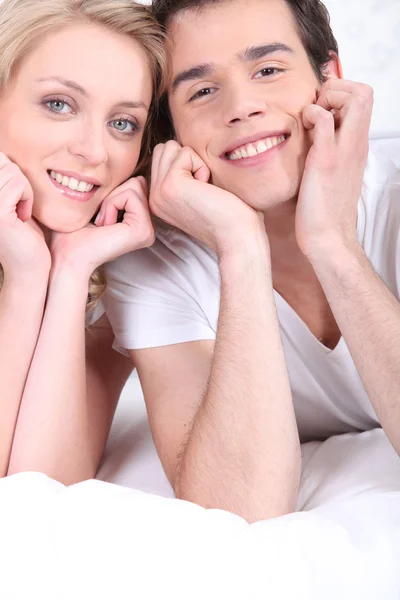 ベッドの上に敷設幸せな若いカップル — ストック写真