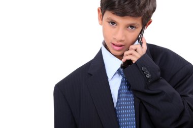 Young boy in adult business suit and cellphone clipart