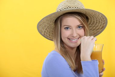 Blond drinking fruit cocktail whilst wearing a straw hat clipart