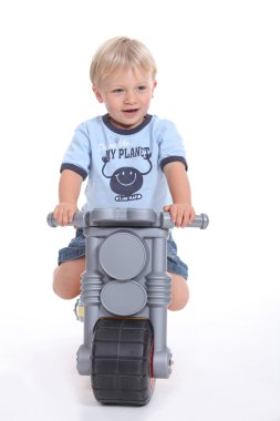 A little boy on his toy motorbike. clipart