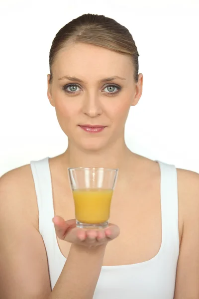 Mulher loira mostrando um copo de suco de laranja — Fotografia de Stock