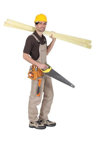 Carpenter holding saw and planks — Stock Photo, Image