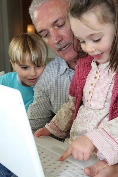 Grootvader en kleinkinderen met laptop — Stockfoto