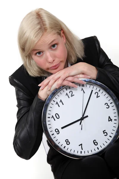 Mujer de negocios rubia apoyada en un reloj grande — Foto de Stock
