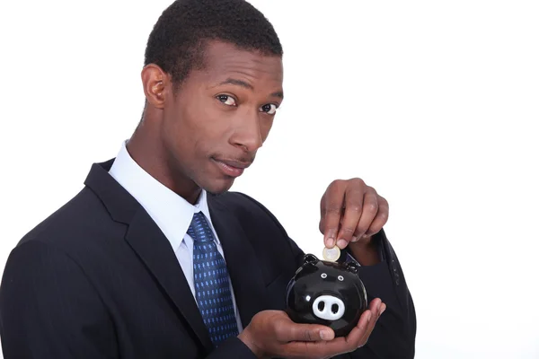 Man putting coins in piggy bank — Stock Photo, Image