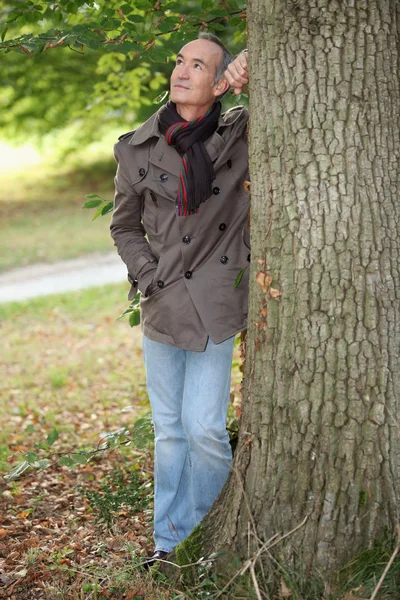 Літній чоловік спирається на дерево — стокове фото
