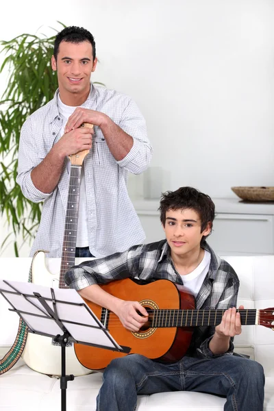 Mężczyzna nauczanie nastoletniego chłopca na gitarze — Zdjęcie stockowe