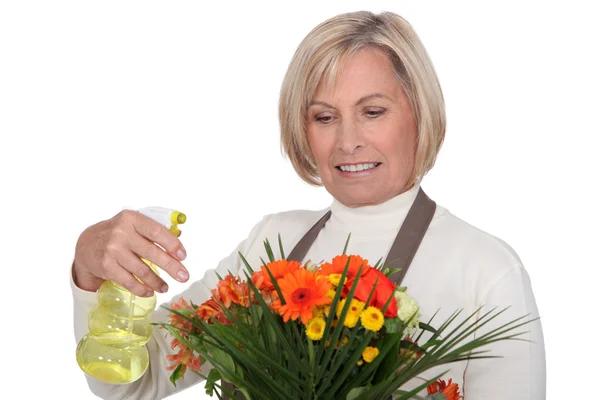 Fleuriste féminine senior pulvérisation d'eau sur bouquet — Photo