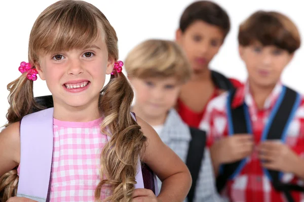 Schulmädchen mit Schulranzen und Jungen im Hintergrund — Stockfoto
